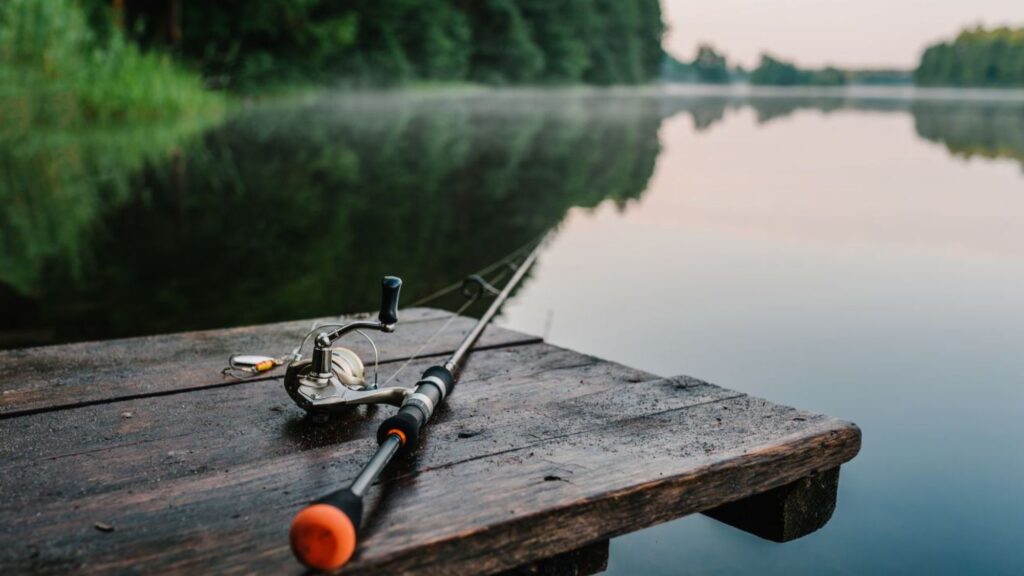 A fishing rod and reel resting on a wooden pier, perfect for outdoor activities for physical wellbeing